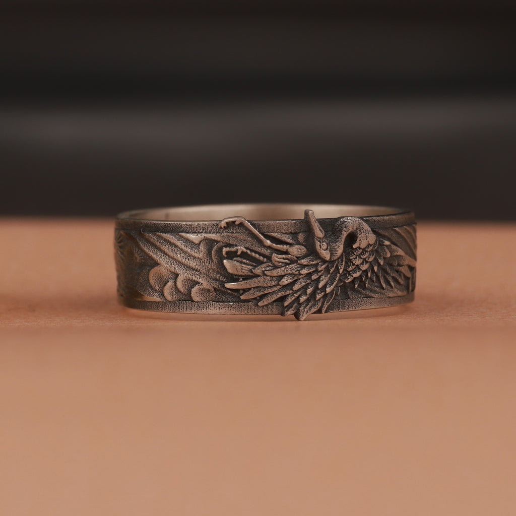 Oxidized silver ring with intricate design on a brown surface