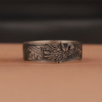 Oxidized silver ring with intricate design on a brown surface