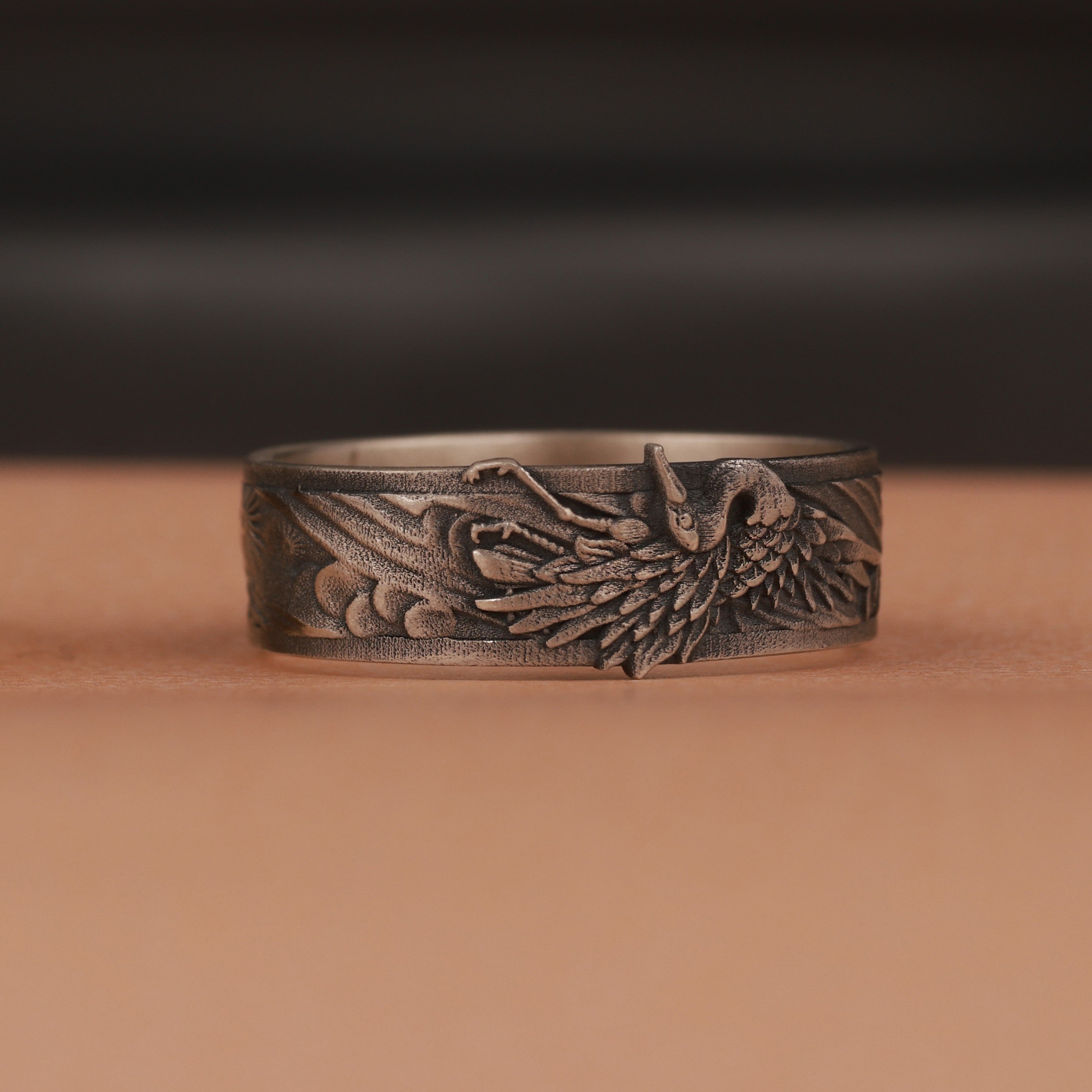 Oxidized silver ring with intricate design on a brown surface