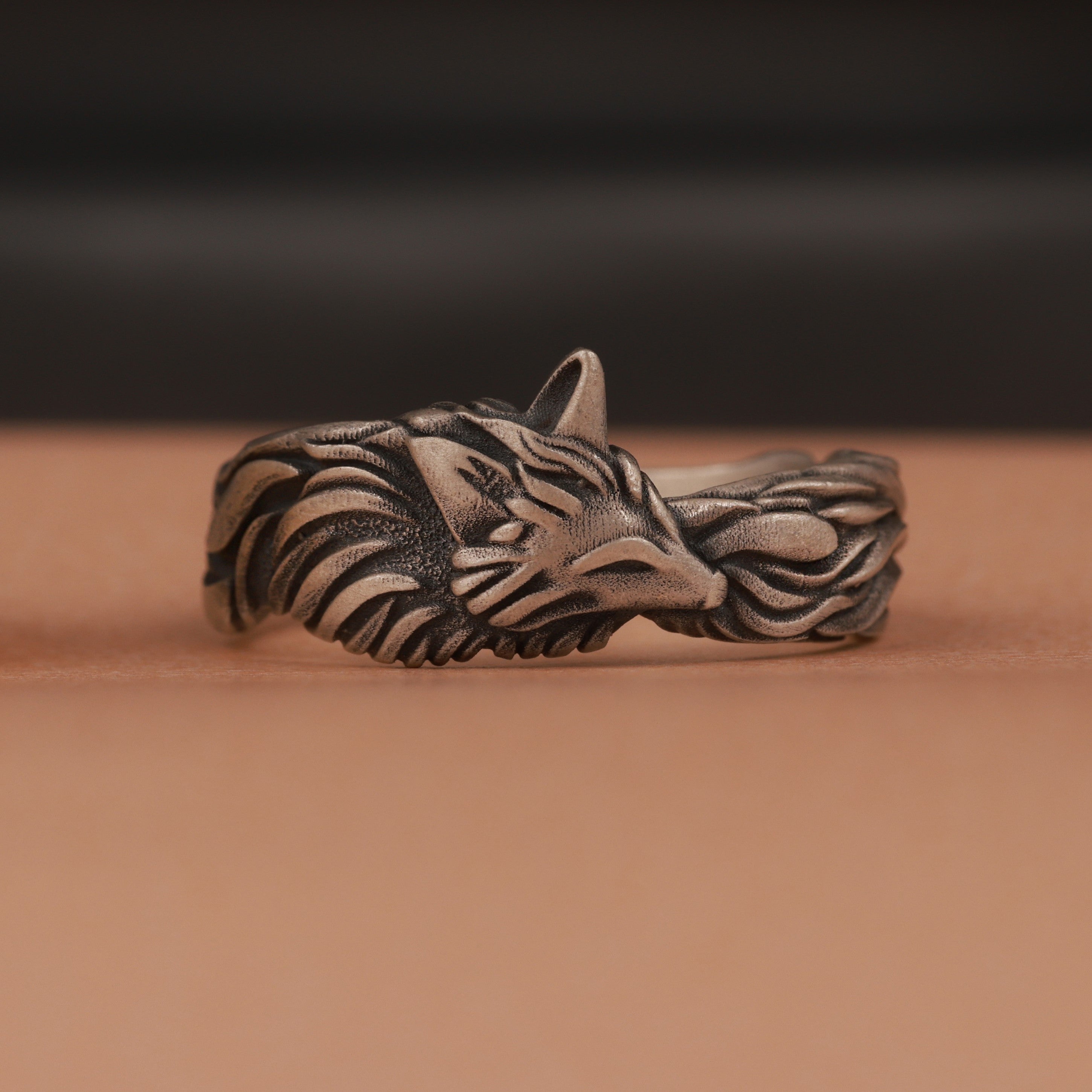 Oxidized silver fox head ring on a brown background