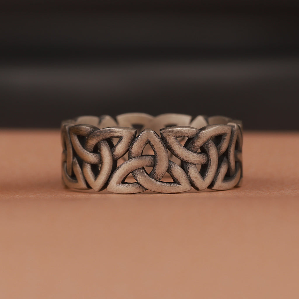 Silver Celtic knot ring on a brown surface with a dark background