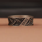 Oxidized silver ring with intricate design and 'INRI' engraving on a brown background