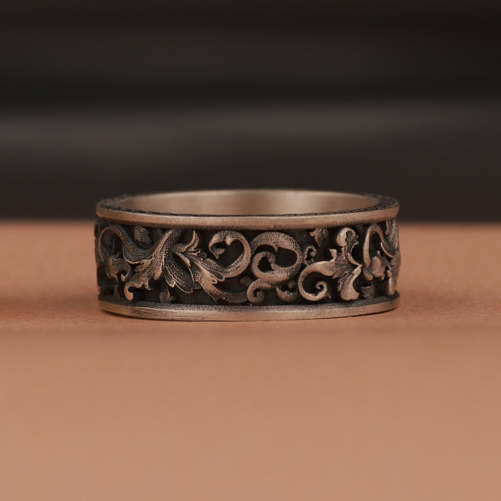 Decorative silver ring with intricate designs on a brown surface