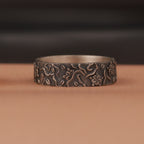 silver ring with floral patterns on a brown surface
