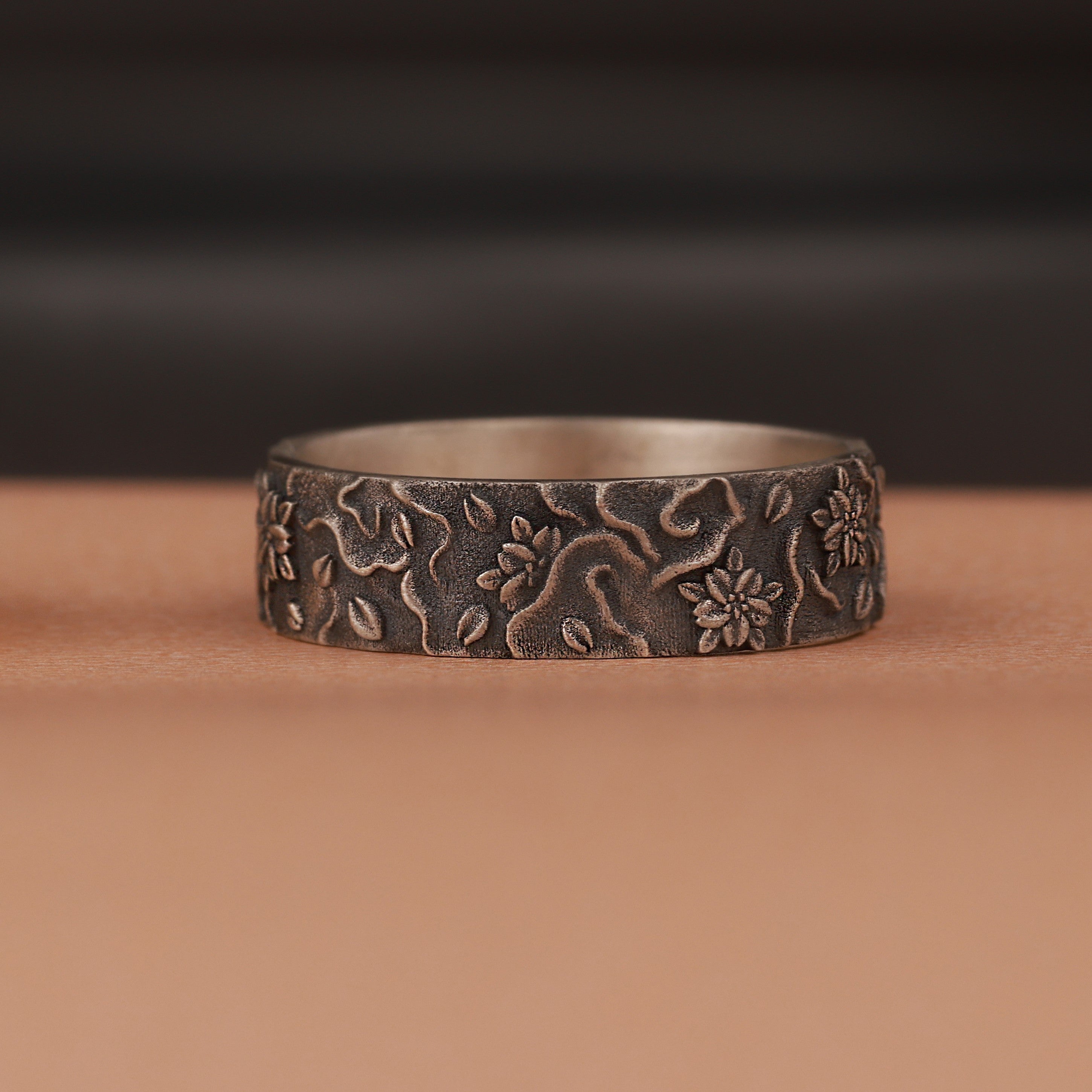 silver ring with floral patterns on a brown surface