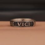 Bronze ring with 'veni vidi vici' engraving on a brown surface