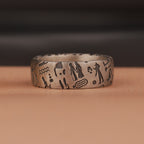 Silver ring with engraved Egyptian symbols on a brown surface