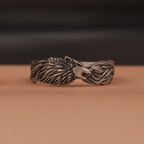 Oxidized silver wolf head ring on a brown surface with a dark background