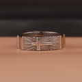 Polished silver ring with cross design on a brown background