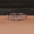 Polished silver ring with cross design on a brown background